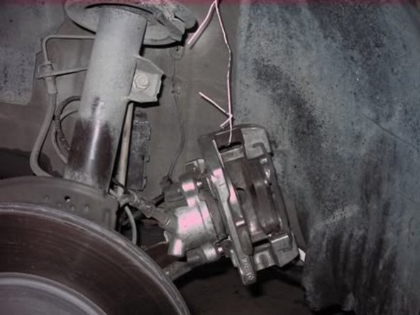 Remove brake caliper and suspend with wire from strut being careful to not bend the brake hose.