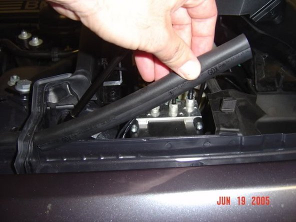 CAREFULLY cut or unwrap the felt tape that holds the hood switch wires to the larger wiring bundle, and pull them up toward the windshield. You will need to remove the cover for the brake resevoir, and it is also easier if you remove the short weatherstripping piece and plastic braket that are shown in the pictures below: