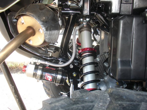 Install rear right shock with the hose facing outside of vehicle and facing the rear of vehicle as shown.