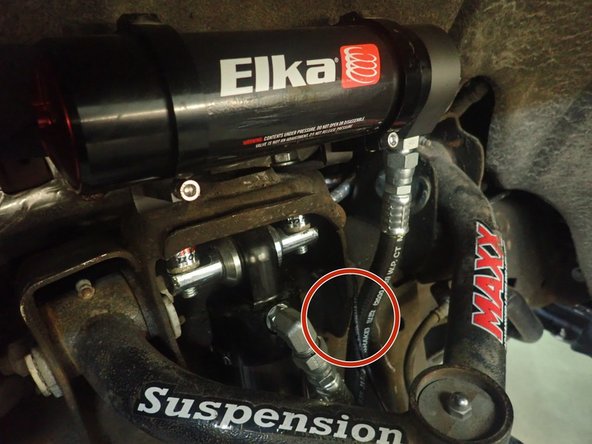 Sit reservoir into bracket's clamps, then place the reservoir in a way to place hose properly. BE CAREFUL TO NOT OVERBEND THE HOSE OR MAKE IT RUBBING ON UPPER SHOCK MOUNT IN THE AREA SHOWED BY RED CIRCLE.