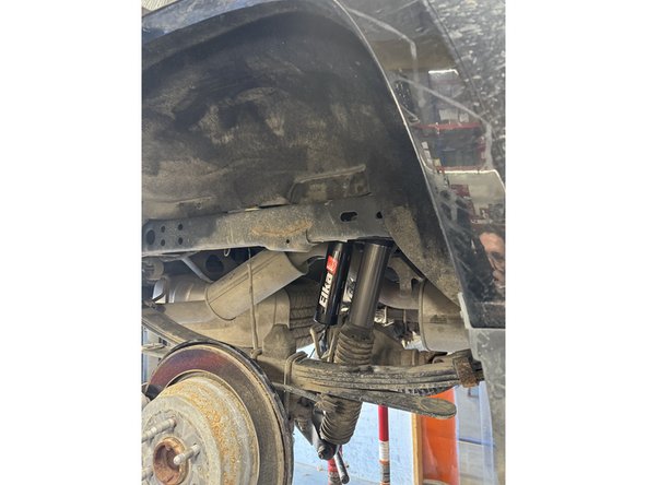 Using an underhoist stand or a jack, lift rear axle to be able to install lower bolt.