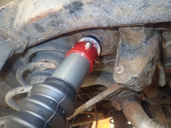 On the shock upper mount, remove nut, first washer and first isolator. Apply supplied white grease on top of upper isolators.