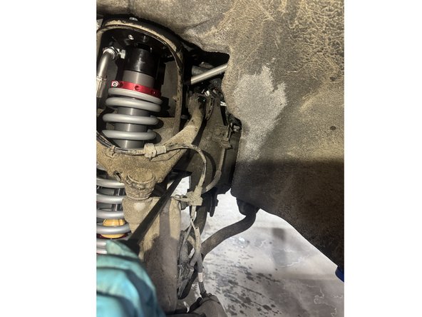 Pry the assembly as shown in the picture to help remove and reinstall the shock.