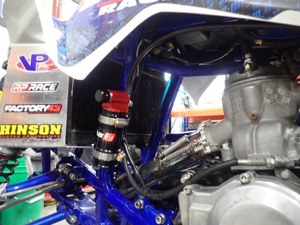Pass the hose along the frame as shown and fix reservoir to the front of atv as shown with supplied rubber mount kit. (Legacy reservoir shown)