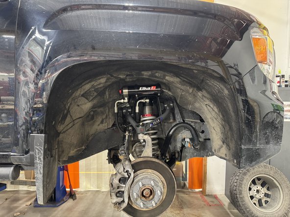 Install the Elka shocks using OEM lower bolts and the provided upper bolts. The hoses must face the rear of vehicle as shown.