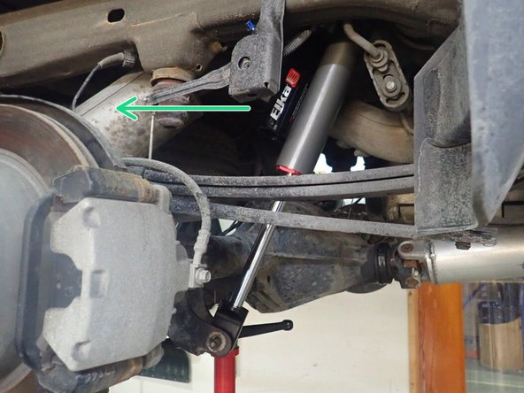 LEFT SIDE: Install rear left shock with the head to the top and the reservoir facing front of the vehicle as shown by yellow arrow..