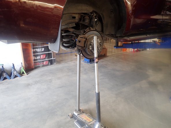 Using an underhoist stand or a jack, lift slightly rear axle to remove tension on shocks bolts.