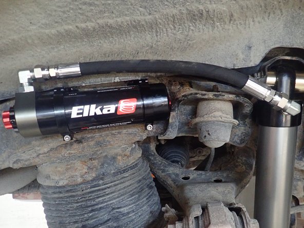 Sit reservoir into bracket's clamps, then place the reservoir in a way to place hose as close to the frame as possible without touching it.