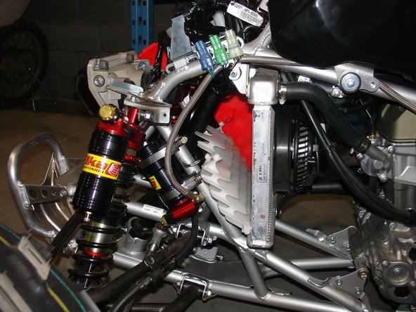 Attach the reservoir to the front of the frame (on the left side) using the provided rubber holders and metal collars (torque to 6 lb.in). The compression adjustment knobs should be facing the front of the quad for convenient access and should be at the bottom of the reservoir. Secure the hose to the frame using zip-ties.