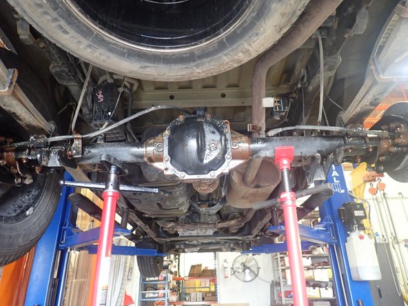 Using an underhoist stand or a jack, support rear axle to remove tension on bolts .