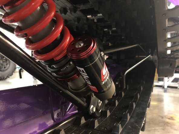 Lower the snowmobile completely and re-install the limiter strap.