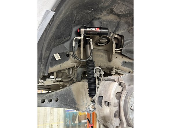 With only the lower rubber bushing on shock's stud, compress the shock and slide the upper stud in place.