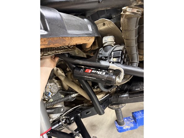 Install the shock as shown, with the head at the top and the hose facing outward.