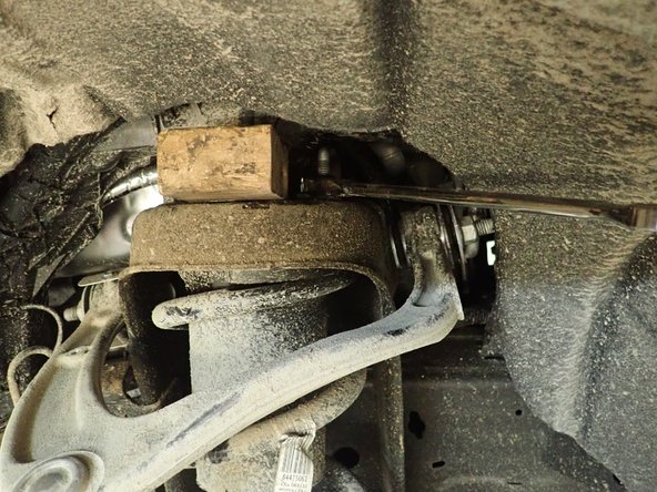 Remove plastic caps on upper shocks studs, then unscrew the 3 upper nuts.