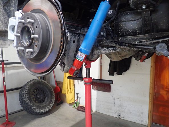 Using an underhoist stand or a jack, lift the rear axle to remove the load on the shock's bolts.