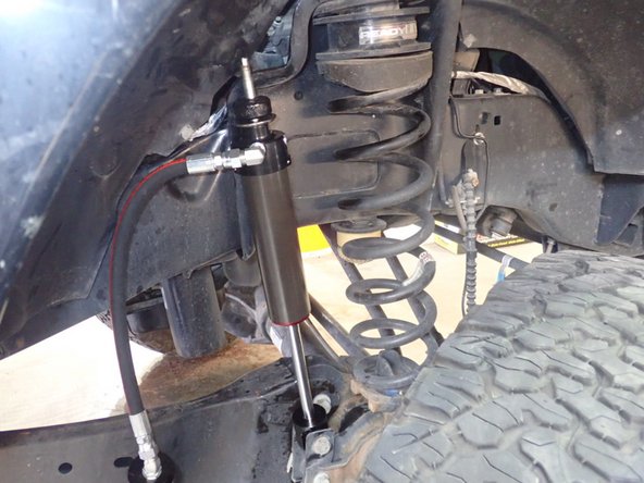 Install new Elka front shocks using lower OEM bolt first without thightening it. Make sure the hose is pointing the rear of vehicle. (Right side shown)