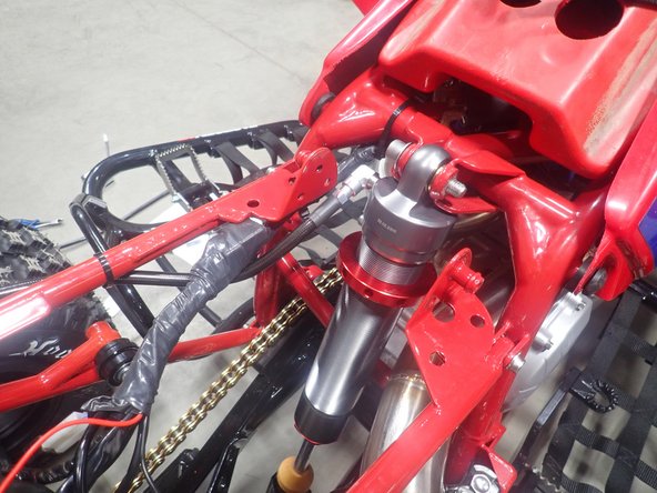 Pass the reservoir in the left side of subframe and install the shock with the hose facing the rear of atv.
