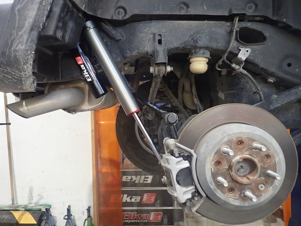 Install supplied washer ON UPPER BOLT as shown by red arrow. Install upper bolt first, then push the shock lower shaft to compress shock and install lower bolt in place.