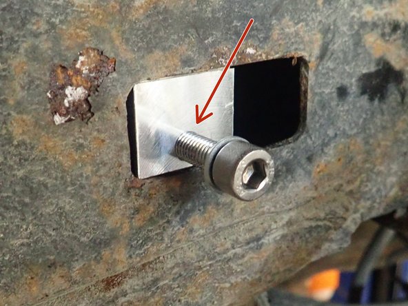 Rectangular piece must be inserted in frame's square hole shown by red circle. Threaded hole in rectangular piece must be installed facing bottom of square hole as shown by red arrow.