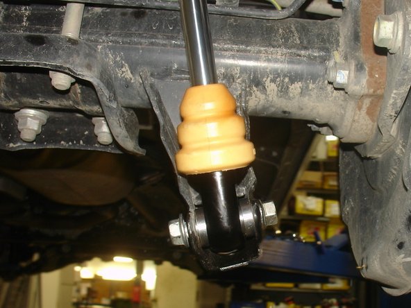 Install upper mount of the Elka shock first. Must have 1 isolator under and 1 over the shock mounting. Do not tighten the nut. The hose must face the outside of vehicle and go to the front . (right side shown)