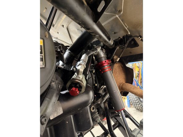 Install the shock as shown, with the head at the top and the hose facing outward.