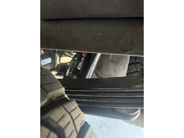 LEFT SIDE; Install rear left shock with head to the top and the reservoir facing the front of vehicle as shown by red arrow.