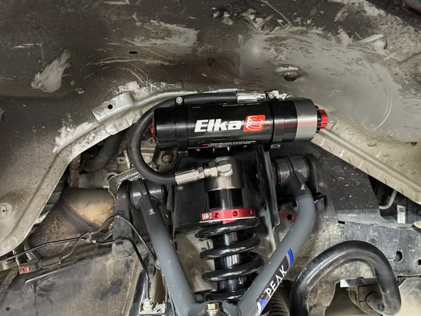 Sit the reservoir into the bracket clamps, then place the reservoir in such a way as to place the hose properly. BE CAREFUL TO NOT OVERBEND THE HOSE OR CREATE RUBBING ON FRAME.