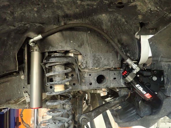 Place shock with the hose facing front of vehicle in place (right side shown)and install upper bolt, then push on lower shock's shaft or move lower axle to install lower bolt. Torque bolts at 80 ft/Lb.