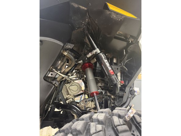 Install the shock as shown, with the head at the top and the hose facing outward.