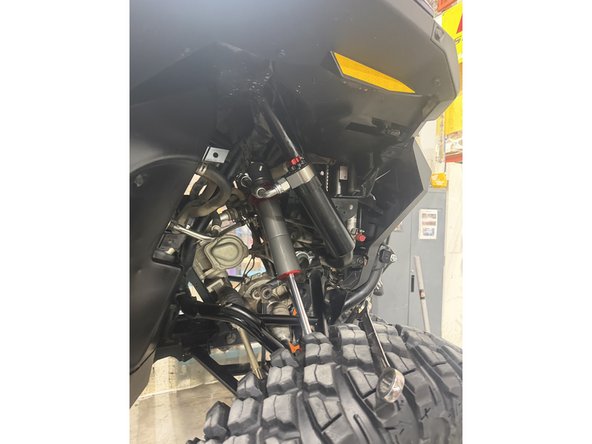 Install the shock as shown, with the head at the top and the hose facing outward.