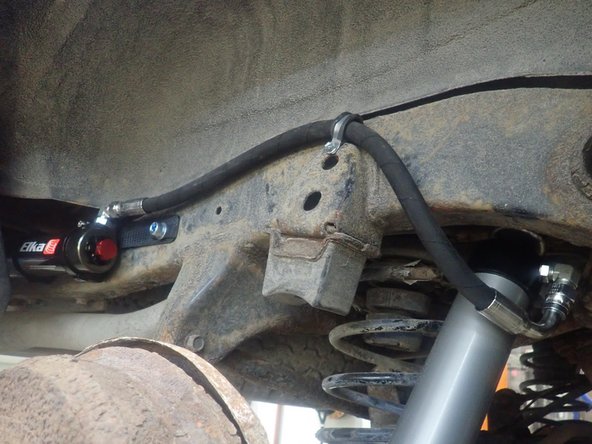 Sit reservoir into bracket's clamps, then place the reservoir in a way to place hose properly. The shock can be turned to align hose as shown. (right side shown).