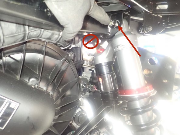 The upper bolt of shock must be installed in the OUTER frame hole as shown by red Arrow.