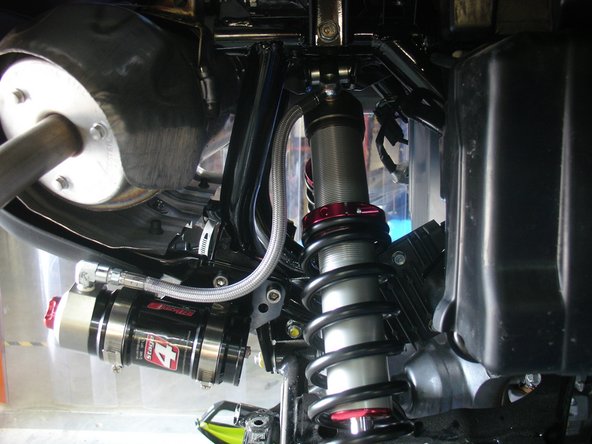 Fix the reservoir on the bracket as shown being careful not to bend the hose too much and ensure that the hose does not come into contact with any component of the vehicle.