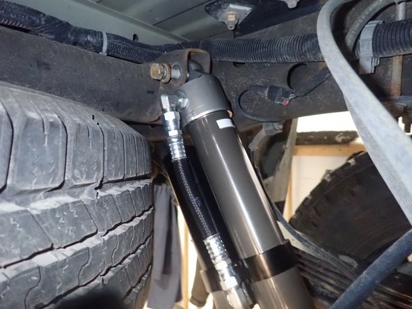 LEFT SIDE: Install rear left shock with head to the top and the reservoir facing the rear of vehicle as shown.