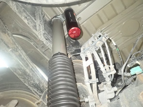 ON REAR LEFT SIDE: install shock with reservoir facing Inside the vehicle as shown.