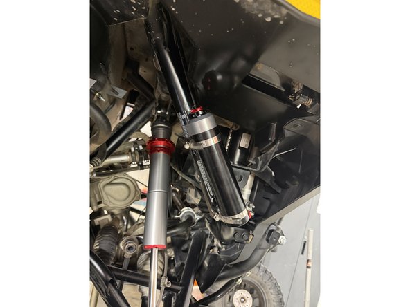 Install the shock as shown, with the head at the top and the hose facing outward.