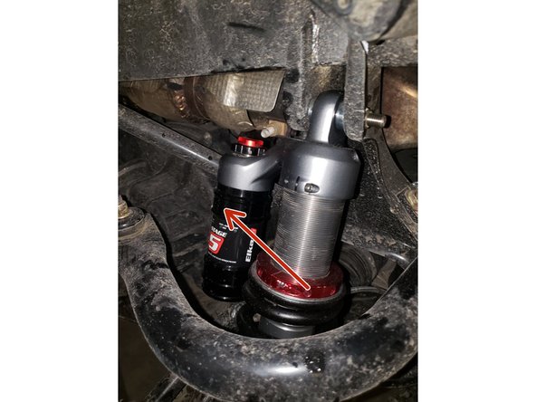 Install the left and right new Elka rear shock with the piggyback reservoir at the top and oriented towards the front of the vehicle as indicated by the red Arrow on the photo.