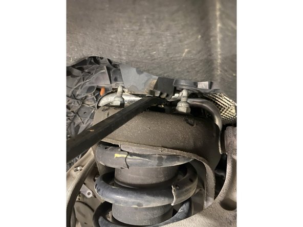 Remove plastic caps on upper shocks studs, then unscrew the 3 upper nuts.