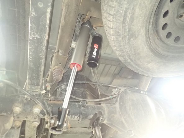 LEFT SIDE: Install rear left shock with the head to the top and the reservoir facing Inside the vehicle as shown.