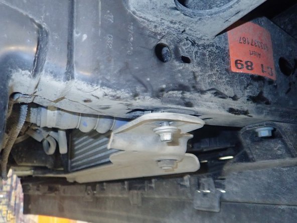 To install reservoir bracket, you have to remove the radiator support lower bolt, slide the bracket between support and frame, then fix the bracket through is center hole as shown ( passenger side shown)