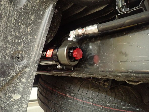 Sit the reservoir into the bracket's clamps, then place the reservoir in such a way as to position the hose properly. BE CAREFUL TO NOT OVERBEND THE HOSE OR CREATE RUBBING ON THE FRAME.