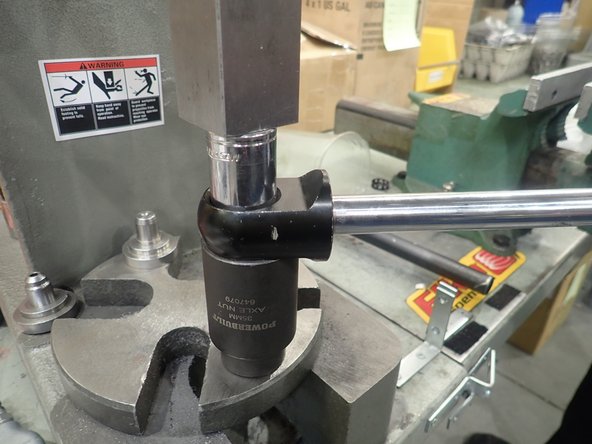 On a  press or a vise:  find a smaller socket to push on the outer race of the bearing and a bigger socket to catch the bearing under shock's end.