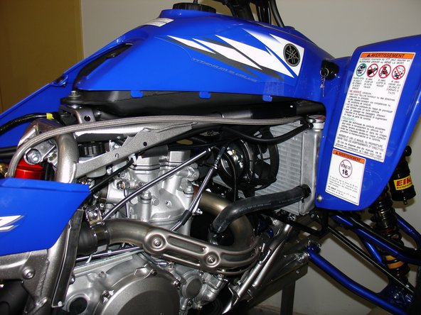 Remove  the seat and right fender, then install Elka shock with the hose facing the right side of the quad. You will have to pass the reservoir into the swingarm first.