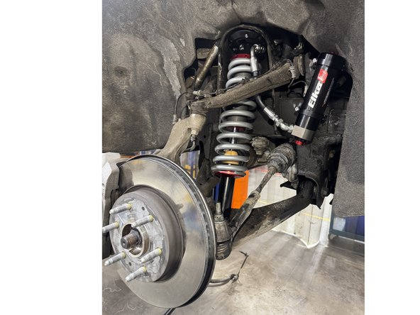 Install the Elka shocks using provided lower and upper bolts. Hoses must face the front of the vehicle as shown (right side shown).