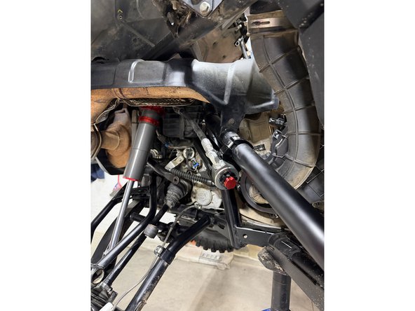 Install the shock as shown, with the head at the top and the hose facing outward.