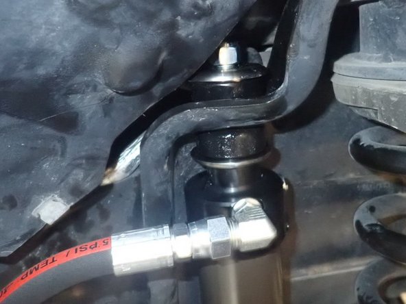 With only the lower rubber bushing on shock's stud, compress the shock and slide the upper stud in place.