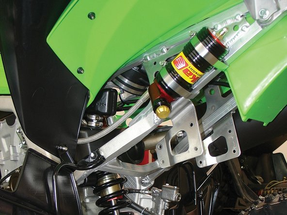 Attach the reservoir over the mounts using the provided collars. Torque to 6 lb.in., making sure the collars are not bent over the subframe, which could cause them to fail. Attach the shock to the lower mount and linkage. Re-install the airbox and seat.