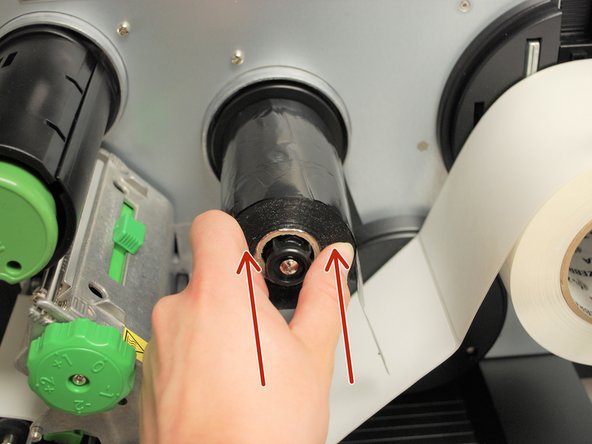 Place the roll of ribbon on the ribbon supply spindle - the black plastic spindle located a little bit above and behind the print head.