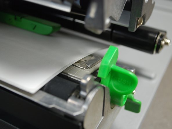 Slide the metallic clip next the to release latch forward until it fits against the close edge of the labels.