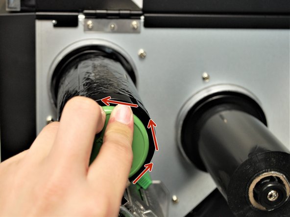 While holding the green 'PUSH' button, rotate the whole spindle counter-clock wise until the ribbon is taut.